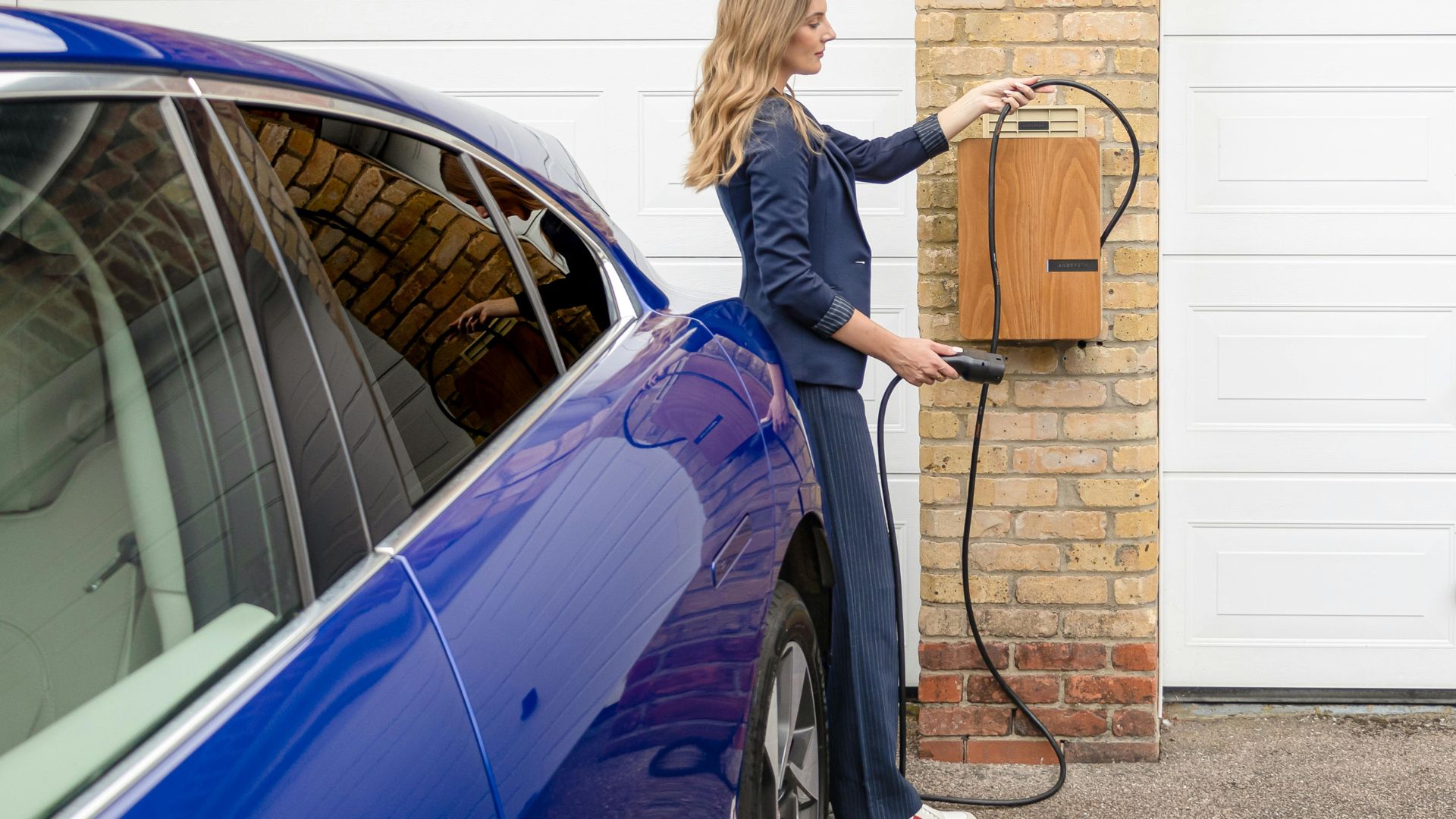 Woman charging electric vehicle at home charging station