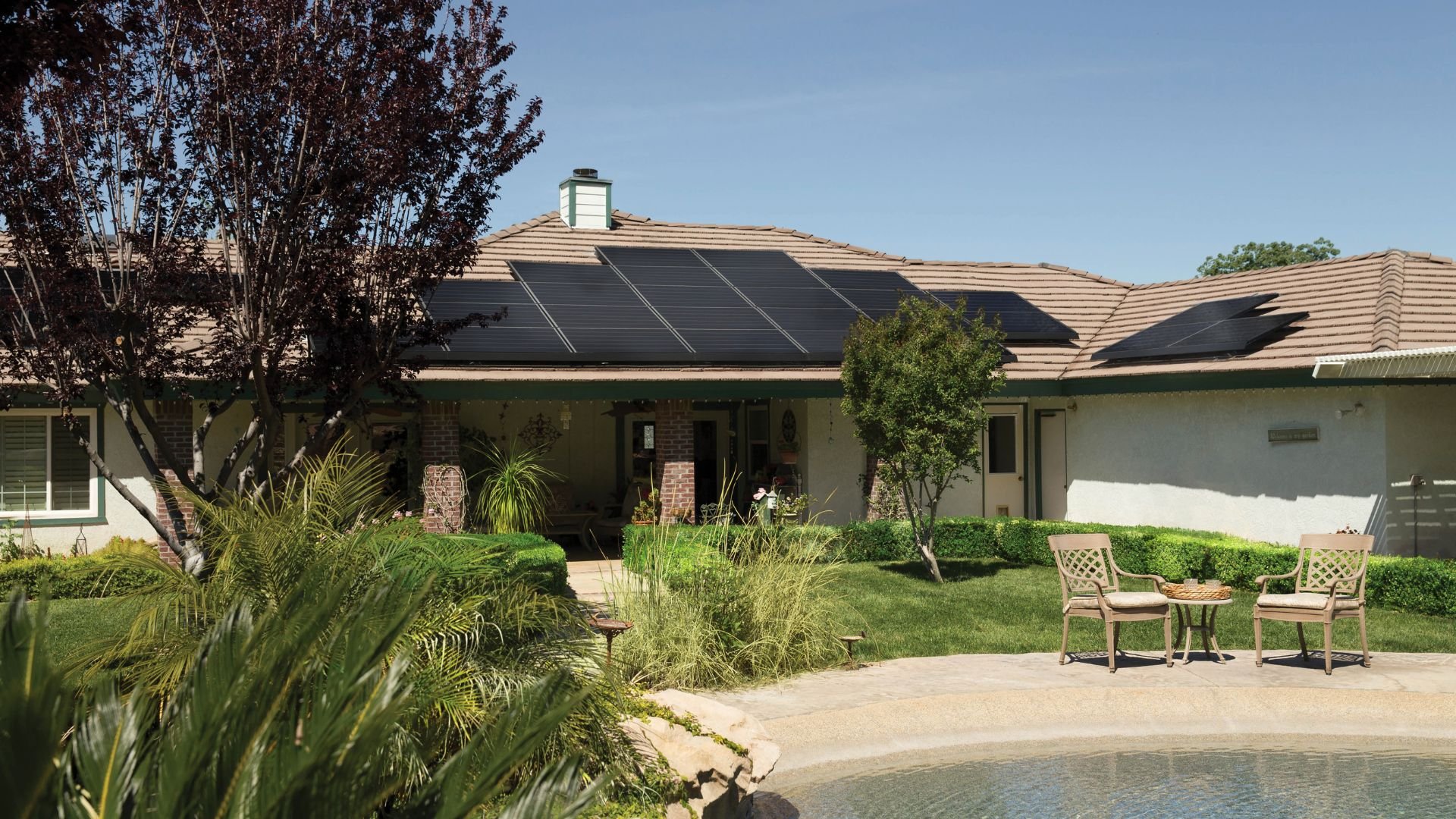 Solar panels on suburban home with landscaped yard and swimming pool